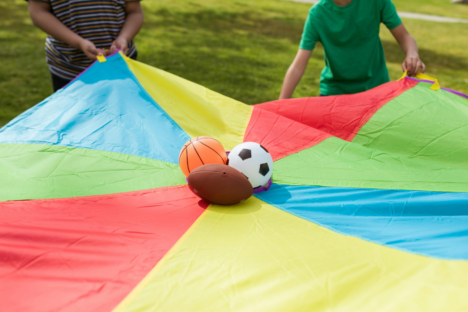 Kinderen spelen met een kleurrijke parachute en ballen tijdens een feestje van Bougez
